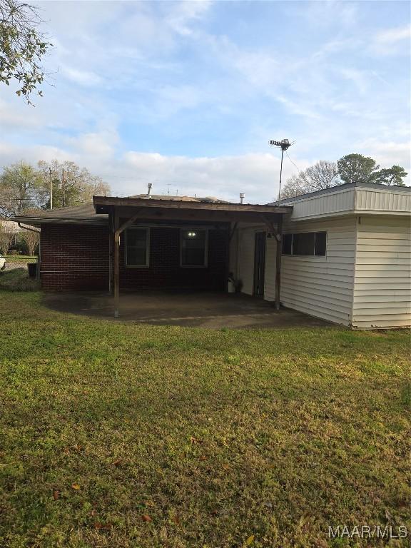 rear view of property featuring a patio area, an attached carport, and a yard