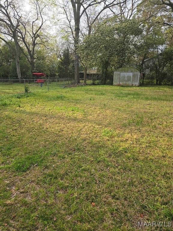 view of yard with an outbuilding, a greenhouse, and fence