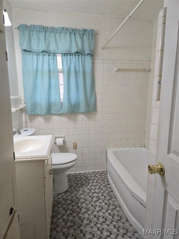 bathroom with toilet, tub / shower combination, tile walls, and vanity