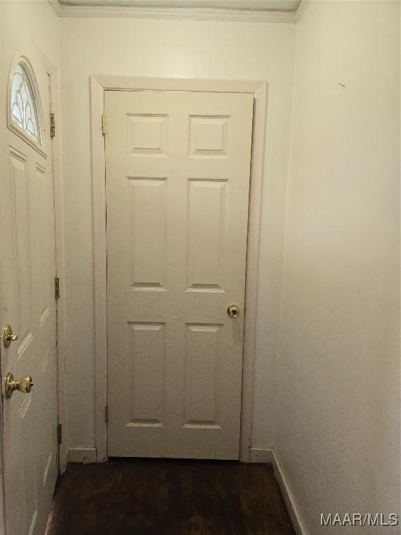 doorway to outside with baseboards, dark wood-type flooring, and crown molding