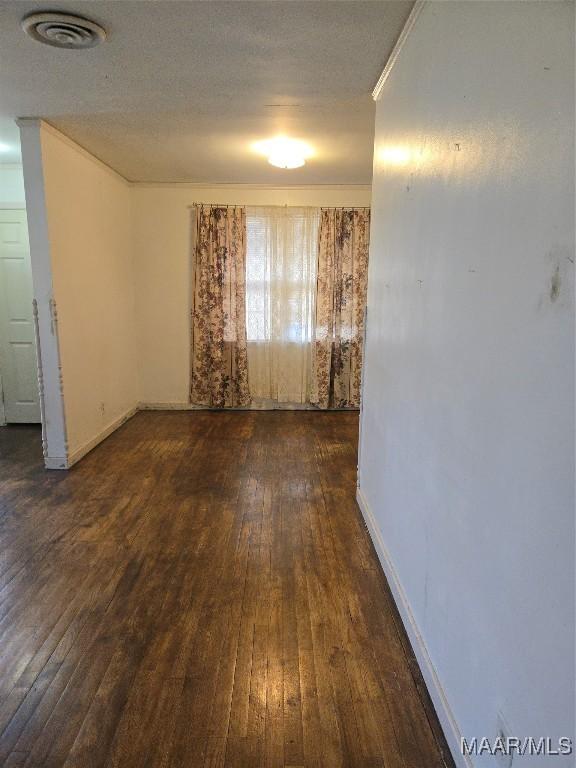 empty room with visible vents, baseboards, dark wood-type flooring, and a textured ceiling