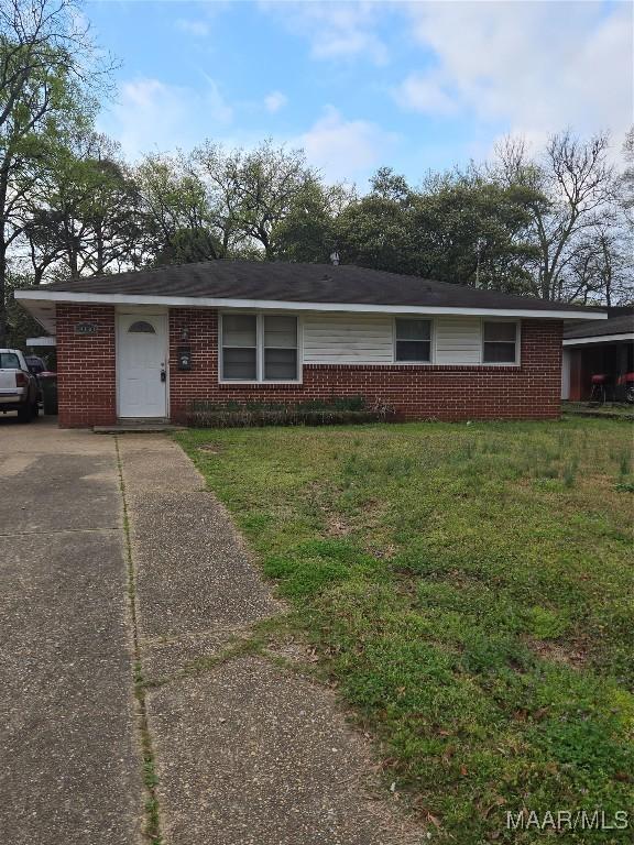 ranch-style home featuring driveway, brick siding, and a front yard