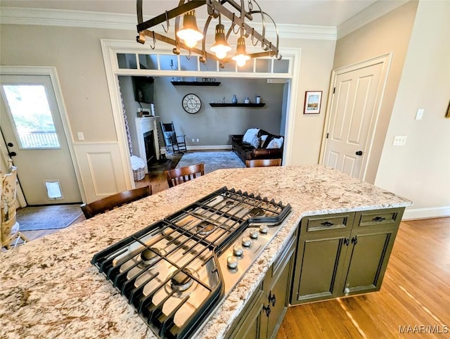 kitchen featuring green cabinetry, stainless steel gas stovetop, crown molding, and light wood finished floors