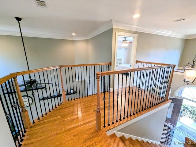 stairway featuring ceiling fan, visible vents, wood finished floors, and ornamental molding