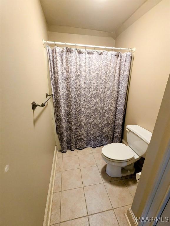 bathroom featuring tile patterned flooring, toilet, and a shower with curtain