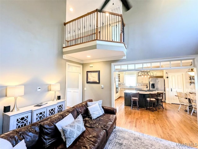 living room with light wood-style flooring and a towering ceiling