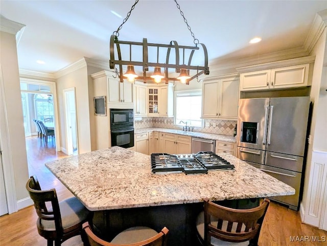 kitchen with a kitchen bar, black appliances, ornamental molding, light wood-style flooring, and tasteful backsplash