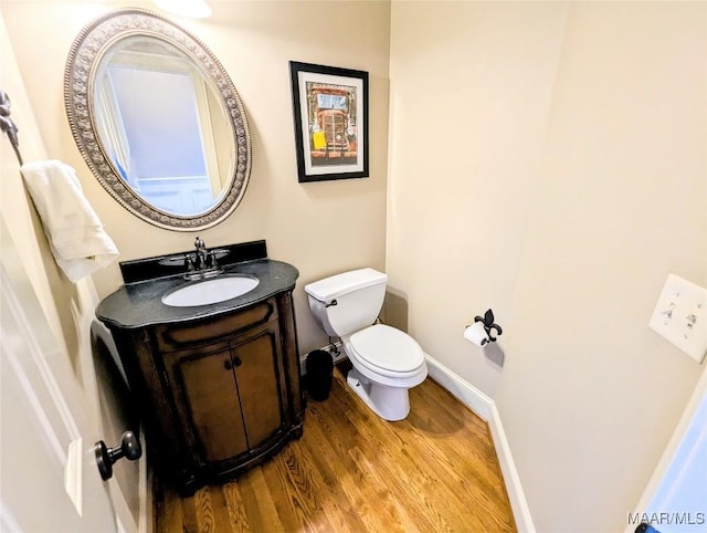 bathroom featuring vanity, toilet, wood finished floors, and baseboards