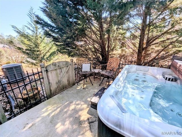 view of patio with a gate, fence, central AC, and a hot tub