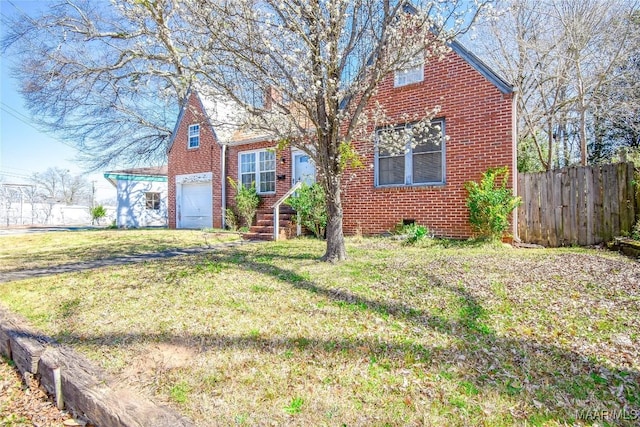 view of front of house with brick siding, a front yard, and fence