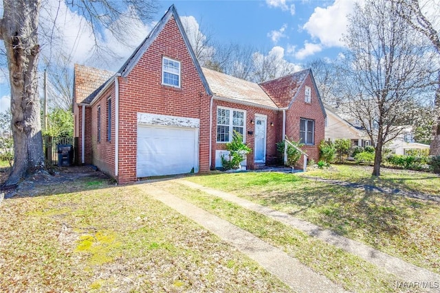 view of front facade with a front yard, brick siding, an attached garage, and driveway