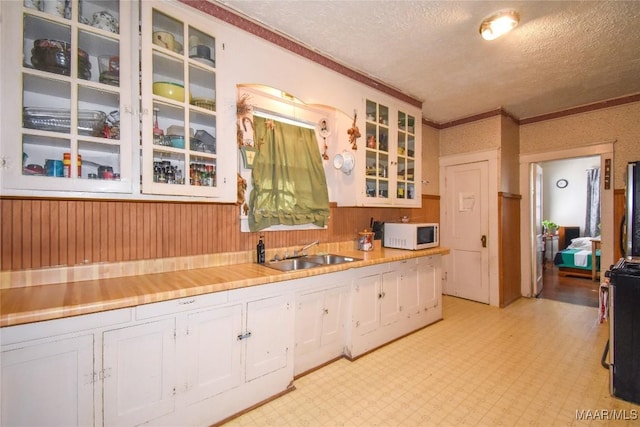 141 S Central Ave, Alexander City, AL 35010 - kitchen with white microwave, white cabinetry, light floors, a textured ceiling, and a sink