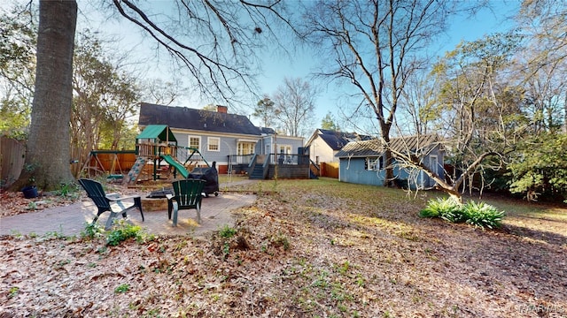 view of yard featuring a patio, an outdoor fire pit, an outdoor structure, a deck, and a playground