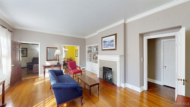 living area with built in features, baseboards, light wood-style floors, and crown molding