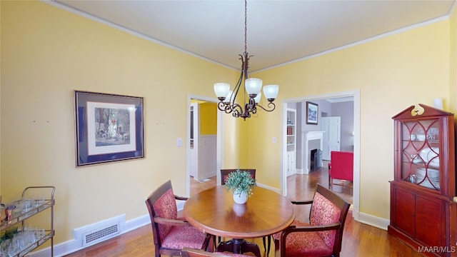 dining area with visible vents, baseboards, an inviting chandelier, and wood finished floors