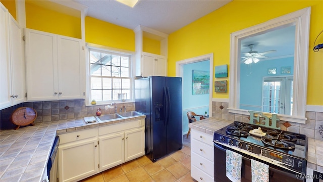 kitchen featuring tile countertops, white cabinetry, black appliances, and a sink