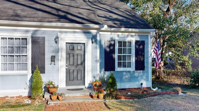 view of exterior entry with roof with shingles