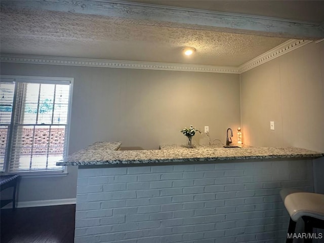 bar with wet bar, plenty of natural light, wood finished floors, and a textured ceiling