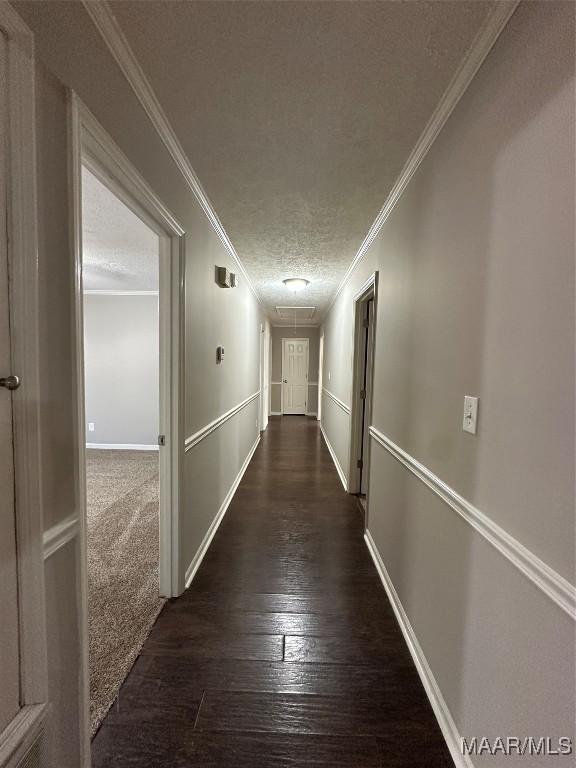 corridor featuring hardwood / wood-style floors, baseboards, attic access, a textured ceiling, and crown molding