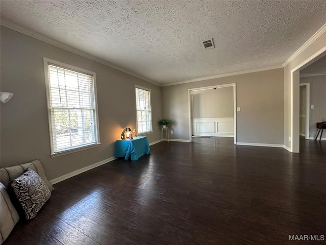 unfurnished room featuring crown molding, wood finished floors, visible vents, and baseboards