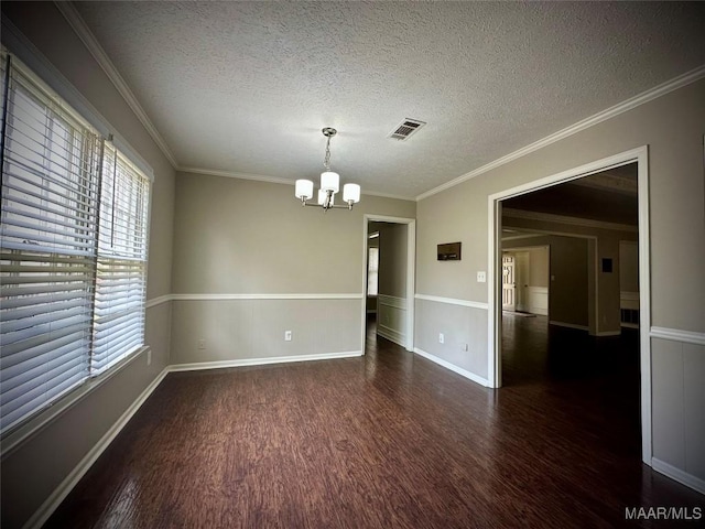 spare room featuring visible vents, wood finished floors, crown molding, and a chandelier