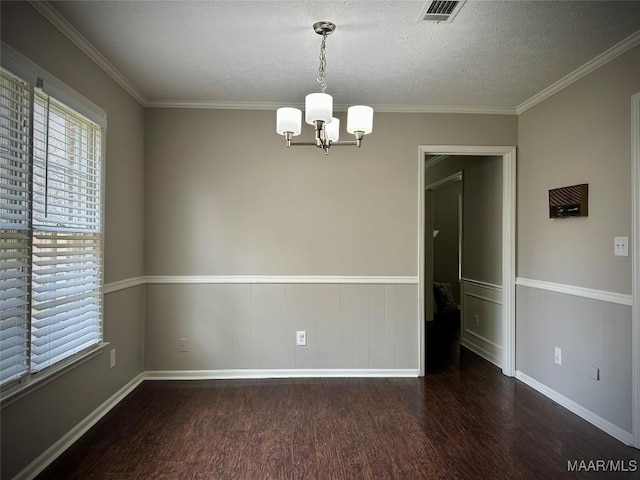 spare room with visible vents, a textured ceiling, wood finished floors, crown molding, and a chandelier