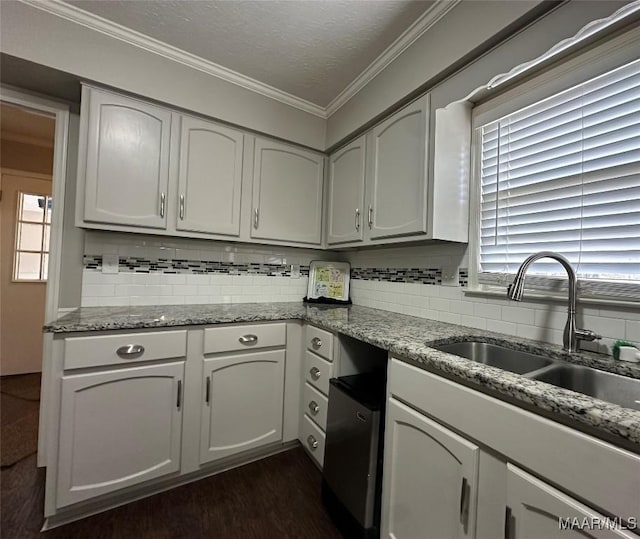 kitchen with a textured ceiling, ornamental molding, backsplash, and a sink