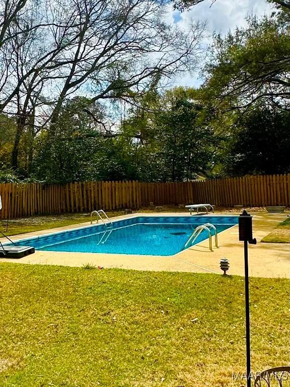 view of pool with a fenced in pool, a diving board, a yard, and fence