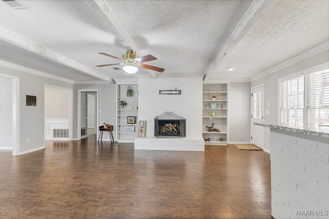 29 Creek Dr, Montgomery, AL 36117 - unfurnished living room featuring beamed ceiling, built in shelves, a textured ceiling, and wood finished floors