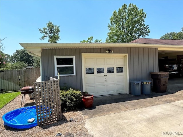 garage with concrete driveway and fence