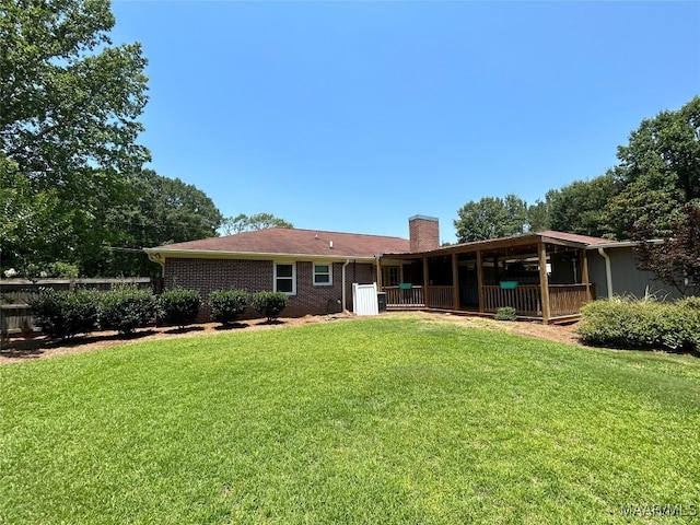 back of property featuring brick siding, a lawn, and a chimney