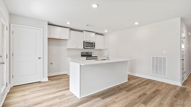 3140 Knotts Dr, Montgomery, AL 36116 - kitchen with appliances with stainless steel finishes, light wood finished floors, white cabinetry, light countertops, and a center island with sink