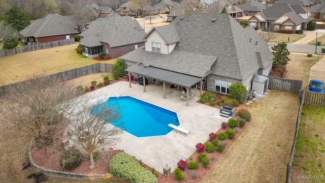 view of swimming pool featuring a patio, a diving board, a fenced backyard, and a residential view