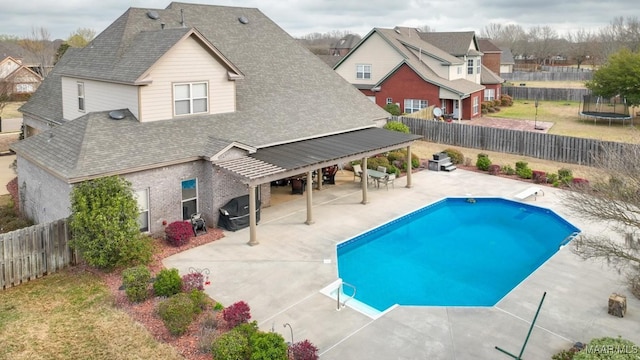 view of pool with a fenced backyard, a patio, a trampoline, and a diving board