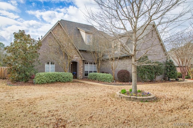 view of front of house featuring brick siding and roof with shingles