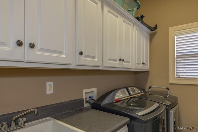 washroom with cabinet space, washer and dryer, and a sink