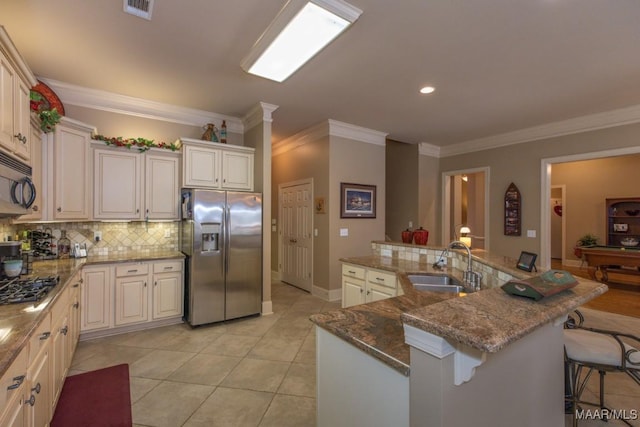 kitchen with visible vents, a breakfast bar area, decorative backsplash, appliances with stainless steel finishes, and a sink