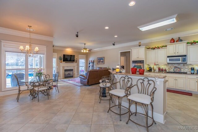 kitchen featuring ornamental molding, a kitchen breakfast bar, stainless steel appliances, light tile patterned flooring, and decorative backsplash