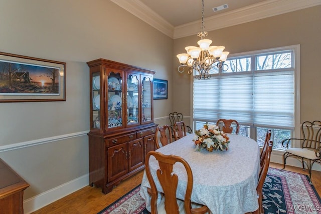 dining area featuring light wood finished floors, visible vents, a chandelier, ornamental molding, and plenty of natural light