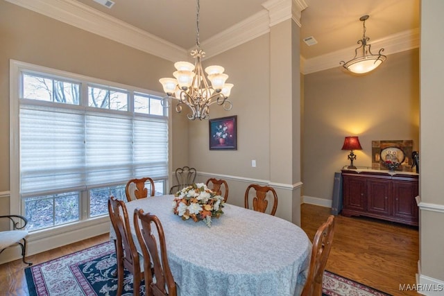 dining space featuring visible vents, wood finished floors, an inviting chandelier, and ornamental molding