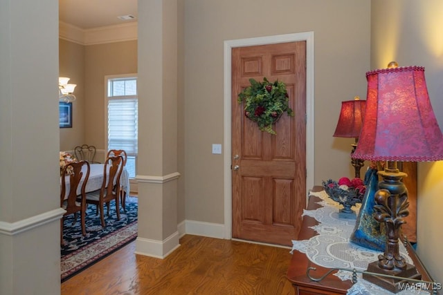 entrance foyer featuring visible vents, baseboards, wood finished floors, and ornamental molding