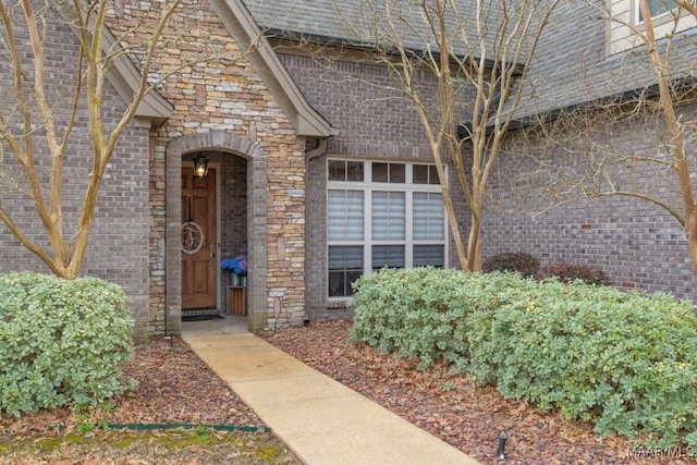 property entrance featuring brick siding, stone siding, and a shingled roof