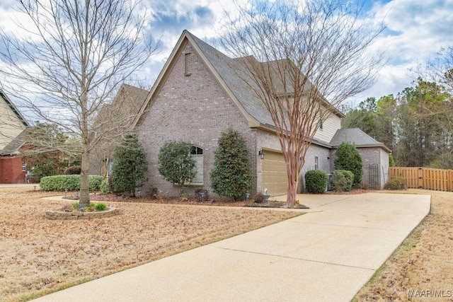 view of front of house with a garage, brick siding, concrete driveway, and fence