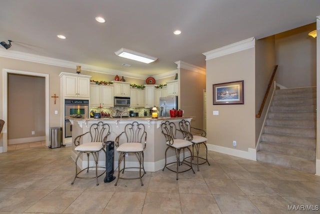 kitchen featuring recessed lighting, stainless steel appliances, decorative backsplash, a kitchen bar, and crown molding