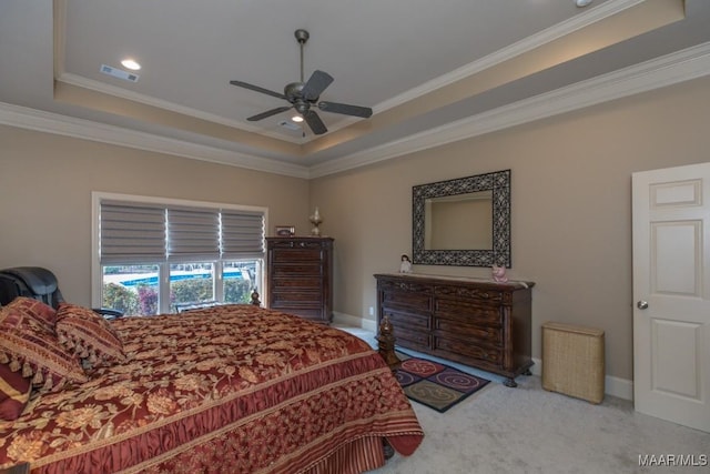 carpeted bedroom with a tray ceiling, baseboards, visible vents, and ornamental molding