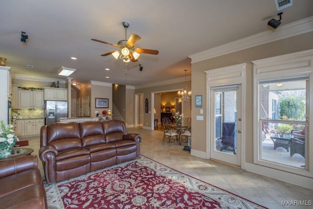 living room featuring light tile patterned floors, visible vents, ceiling fan with notable chandelier, and crown molding