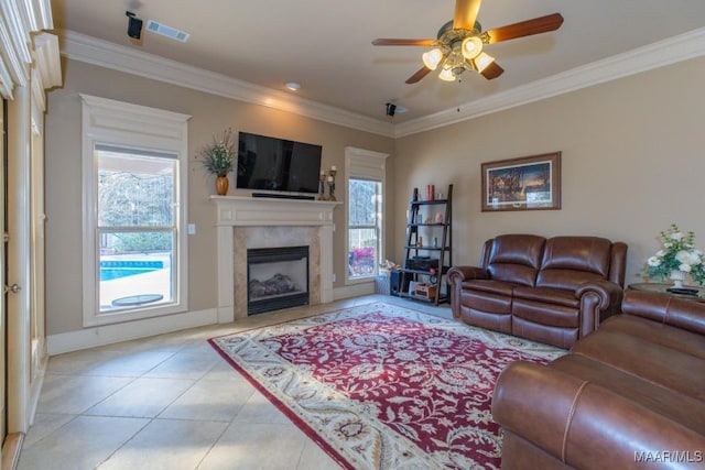 living room with visible vents, a premium fireplace, light tile patterned floors, ornamental molding, and a ceiling fan