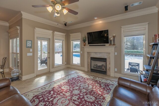 living area featuring tile patterned flooring, visible vents, a healthy amount of sunlight, and crown molding