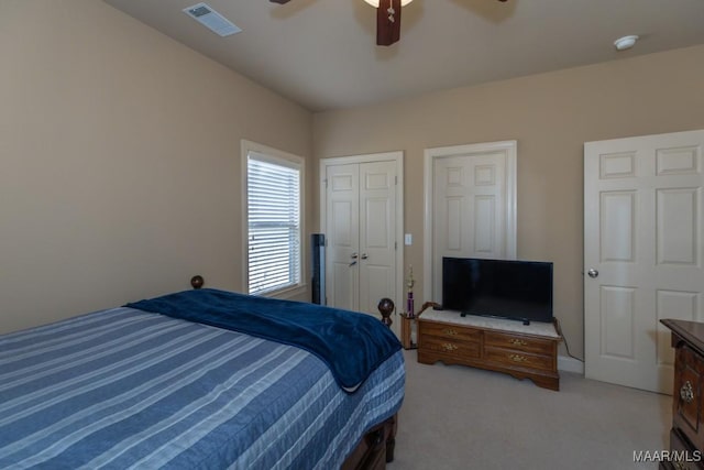 bedroom featuring a ceiling fan, light colored carpet, and visible vents