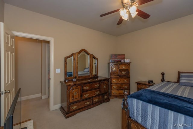 bedroom featuring light colored carpet, a ceiling fan, and baseboards